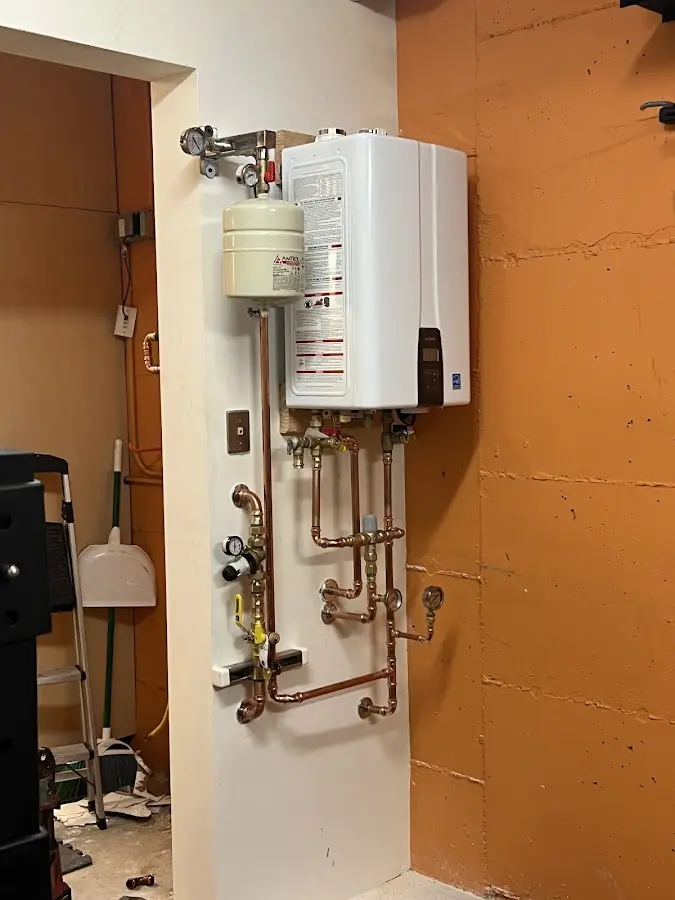 Plumbing technician inspecting water heater connections in Fallowfield
